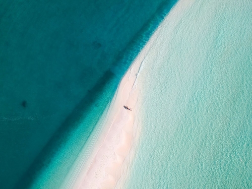 Vue aérienne d'une eau turquoise cristalline et d'un banc de sable aux Maldives.