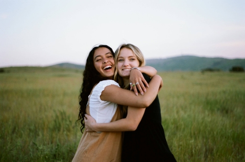Two friends happily hugging in a green meadow