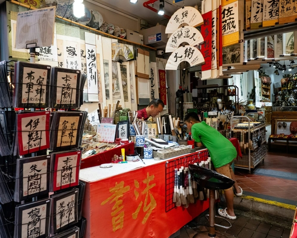 Mann sitzt an einem Verkaufsstand in einem chinesischen Laden – typische Einkaufssituation für Postkarten und Briefmarken.