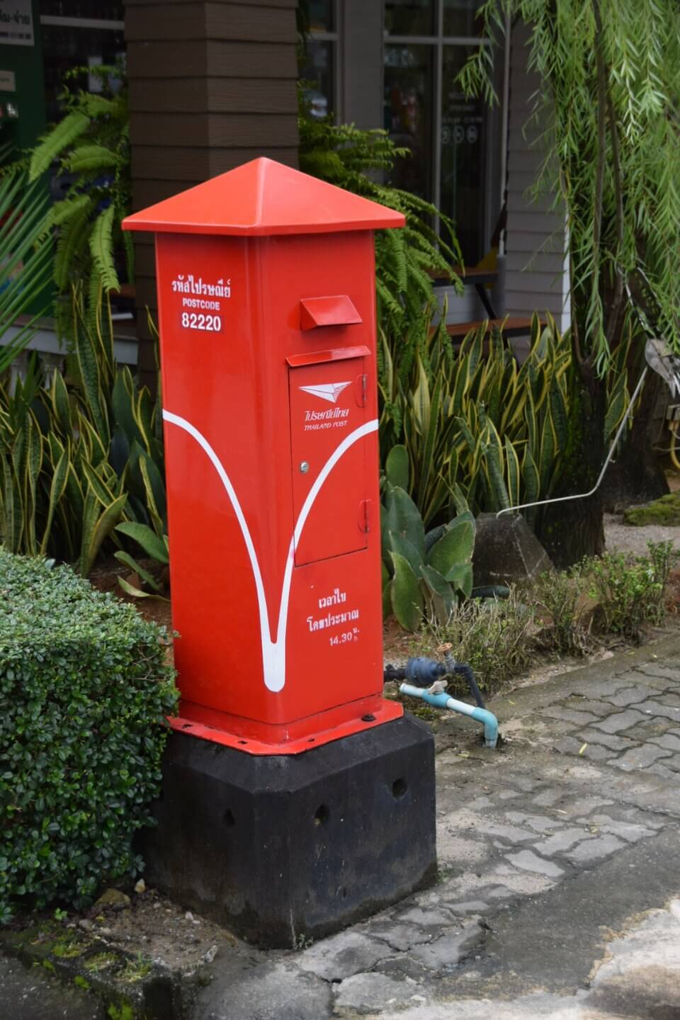 Une boîte aux lettres rouge de Thailand Post au bord d'une rue.