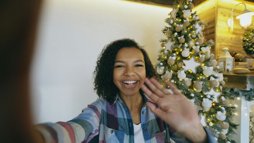 Weihnachtspostkarte: Junge Frau winkt am Weihnachtsbaum