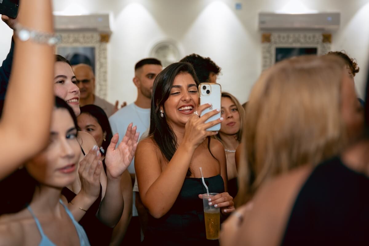 Une femme souriante enregistre des moments lors de la fête avec son smartphone