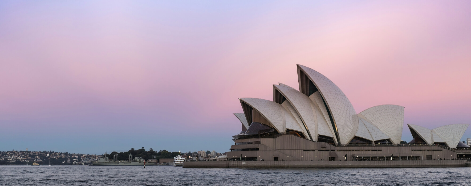 Blick auf das Sydney Opera House und die Harbour Bridge bei morgentlichem Sonnenaufgang.