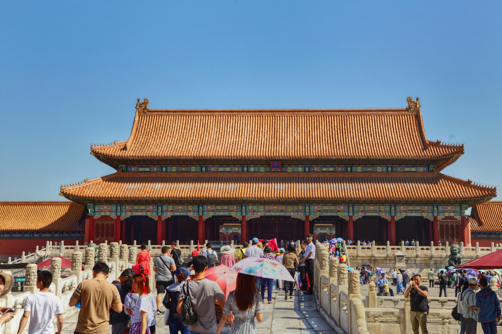 Gruppe von Besuchern läuft vor einem traditionellen chinesischen Gebäude entlang.