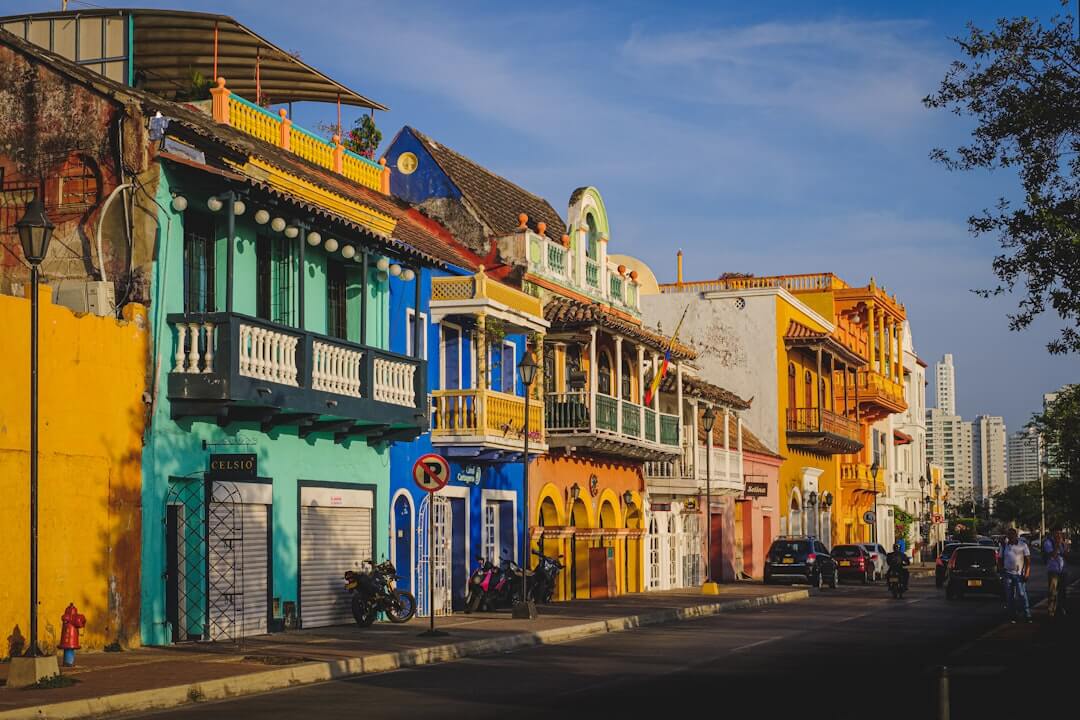 Buntes Straßenbild aus dem Viertel Getsemaní in Cartagena, Kolumbien, mit Autos vor grünen und weißen Häusern.
