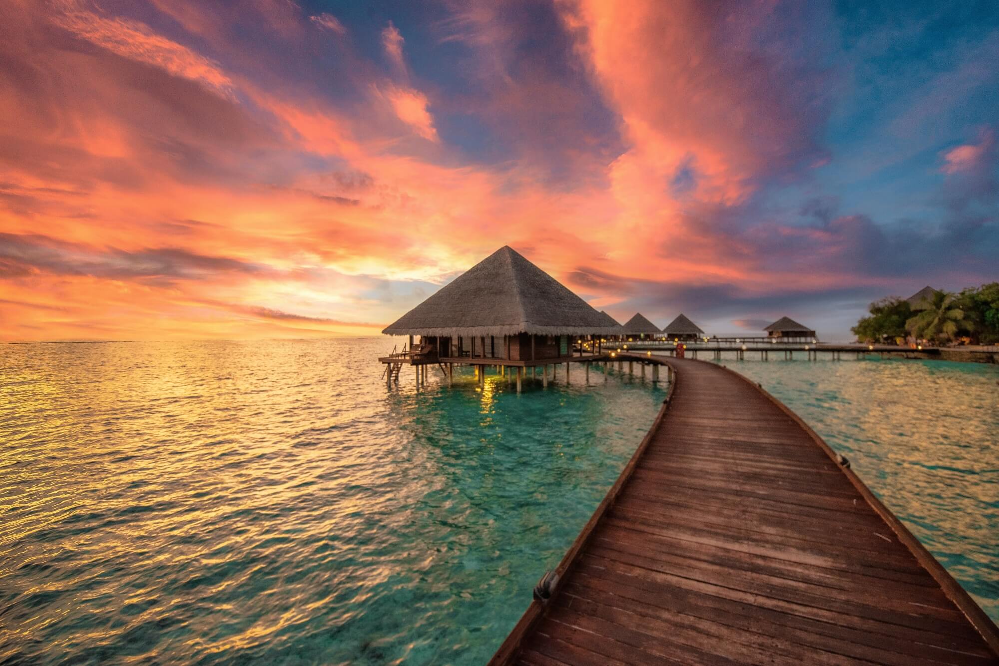 Postkarte mit einem Wasserbungalow bei Sonnenuntergang
