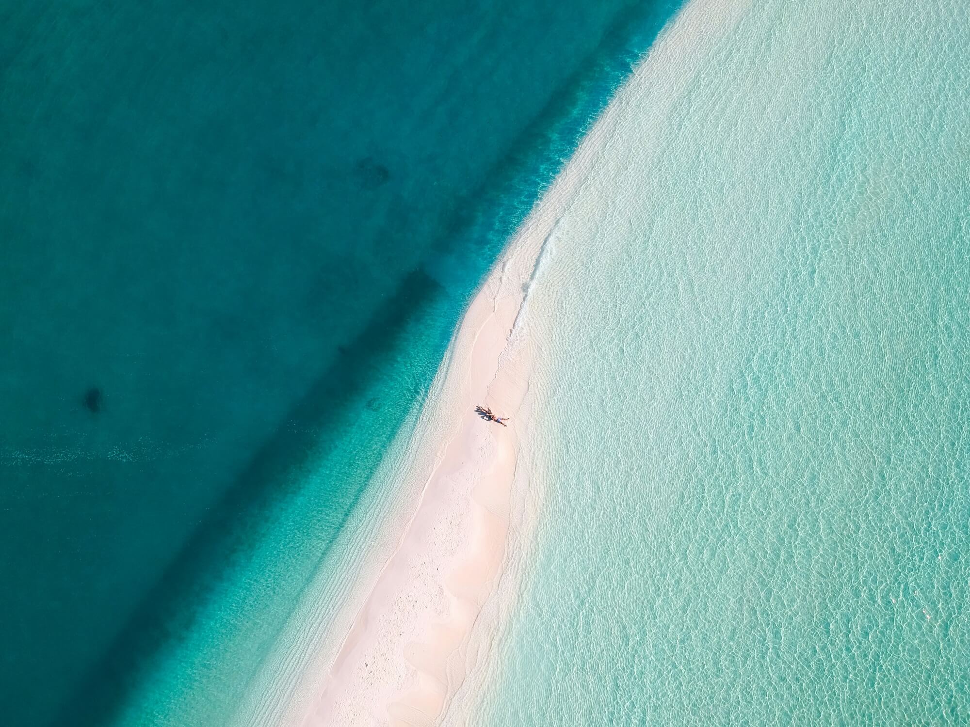 Luftaufnahme über kristallklarem, türkisfarbenem Wasser und einer Sandbankauf den Malediven.