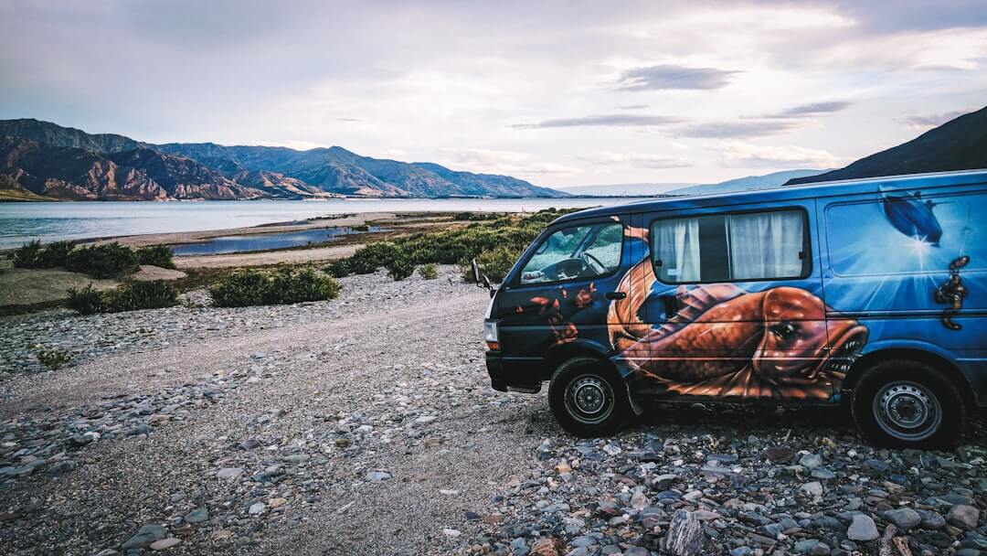 Schwarzer Van auf einer unbefestigten Straße in Neuseeland – typischer Road-Trip durch die Nordinsel.
