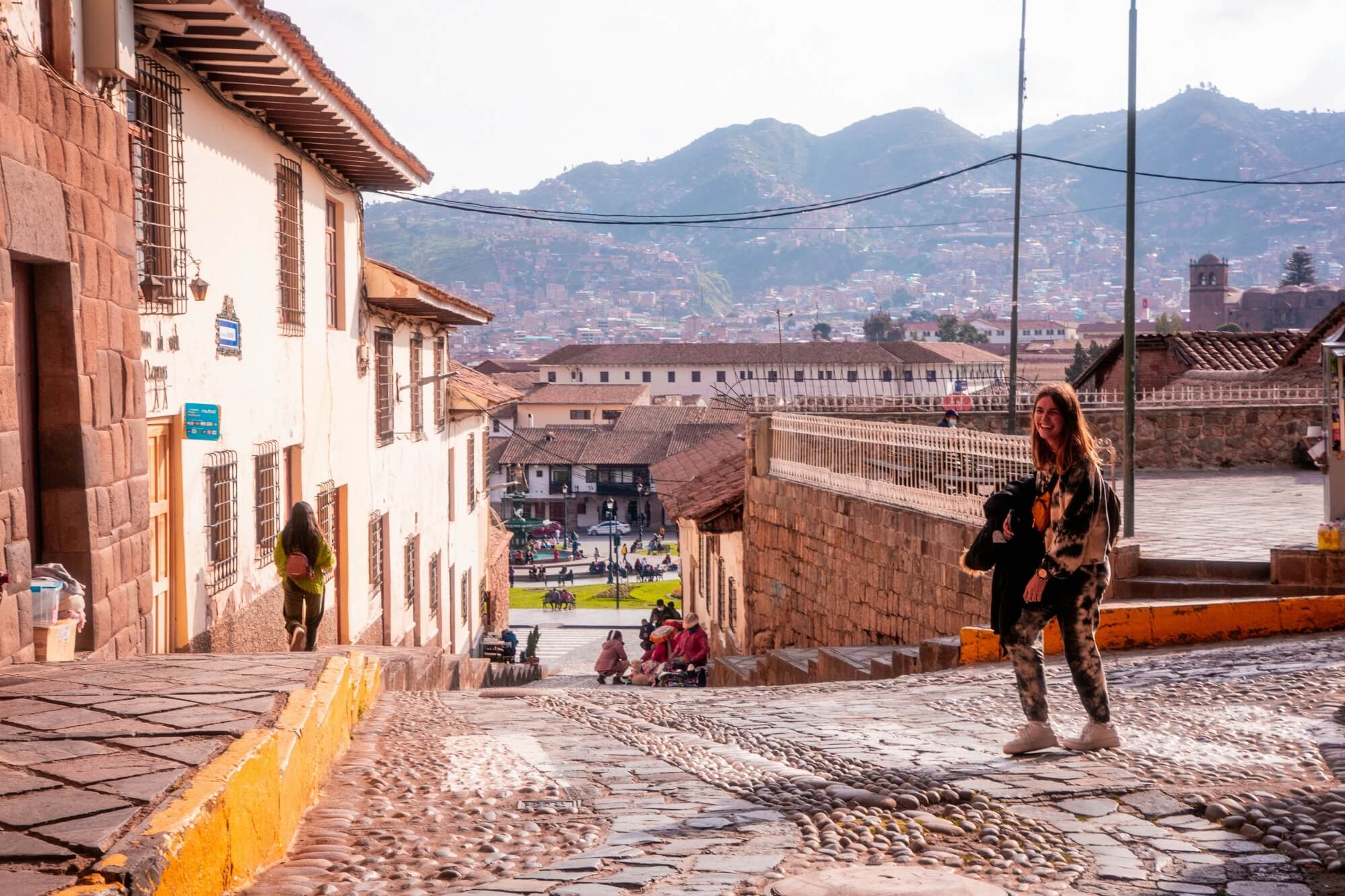 Frau geht eine gepflasterte Kolonialstraße in Cusco, Peru entlang.