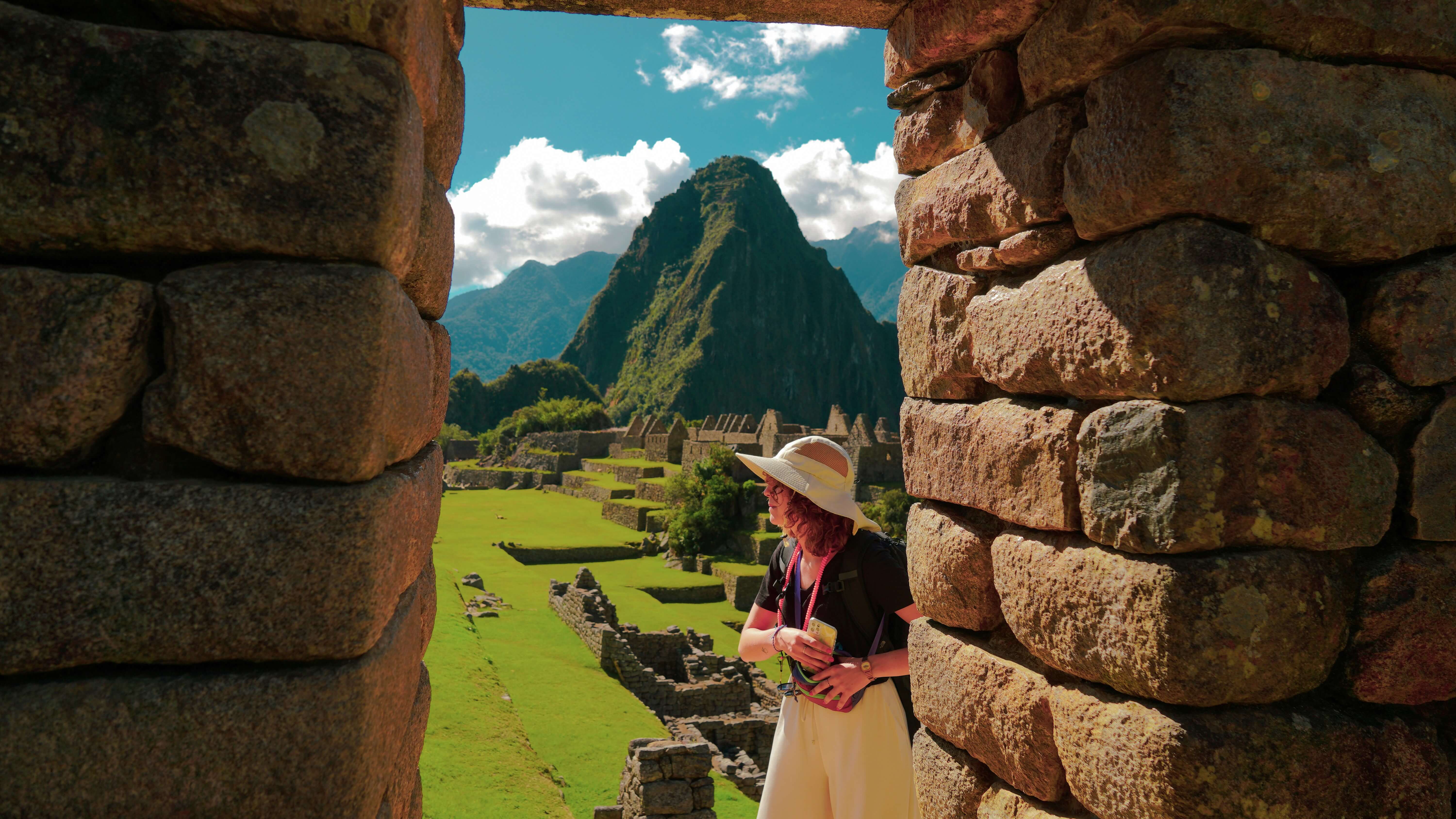 Frau mit Strohhut schaut nachdenklich aus einem Fenster – stimmungsvolle Szene aus Peru.