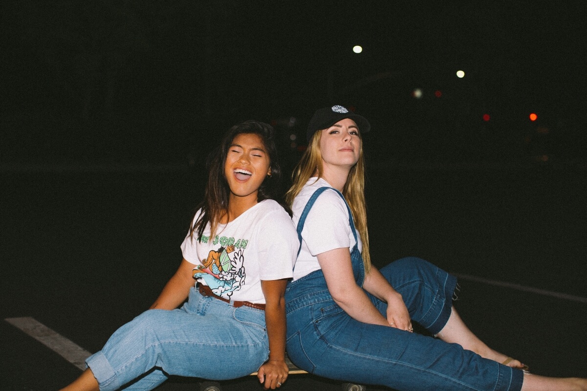 Two friends laughing together on a skateboard
